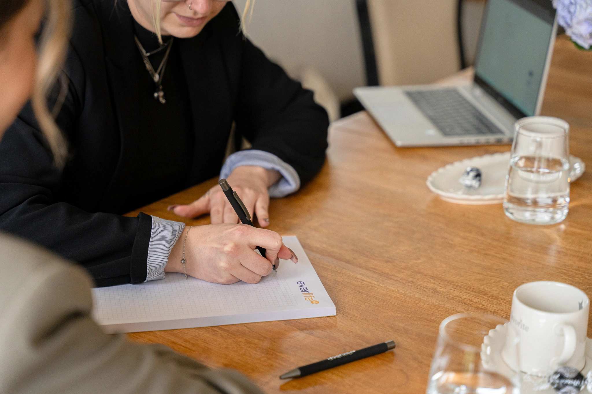 Conseillère Everlife prenant des notes sur un bloc-notes lors d'un entretien avec un client