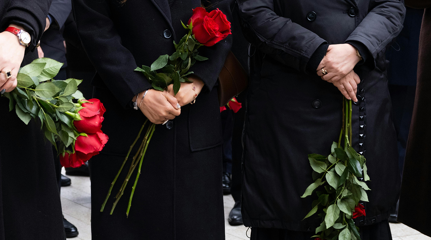 Personnes en deuil tenant des roses rouges lors d'une cérémonie funéraire en Suisse